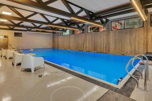 a large swimming pool with blue water in a building at Åros Modern Apartment in Kristiansand