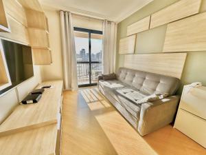 a living room with a couch and a large window at Maison D Stan Moema with washing machine and daily cleaning in São Paulo