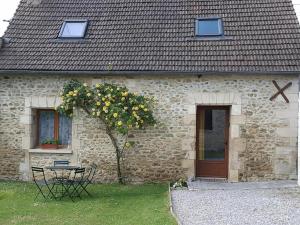 a building with a table and a tree in front of it at maison 2 chambres 4 lits 15mn Aéroport de Beauvais 5mn du château de la trye in Hermes