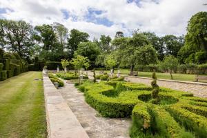 a garden with trimmed hedges and a brick wall at Weston Manor Hotel in Bicester