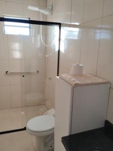 a white bathroom with a toilet and a shower at Casa em meio a natureza próximo ao aeroporto in Chapecó