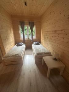 a wooden room with two beds and a table at Uroki Roztocza w Krasnobrodzie in Krasnobród
