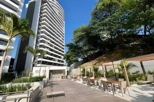 a patio with tables and chairs and a tall building at UNU 1108 Beach Class Ondina: Vista Mar, Piscina e+ in Salvador