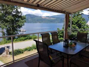 a table and chairs on a porch with a view of a lake at West facing Waterfront Retreat with private beach, dock access & private buoy in Blind Bay