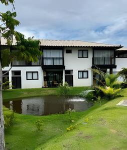 a house with a pond in front of it at UNU 204 Studio Praia do Forte: Wifi, Piscina e + in Mata de Sao Joao