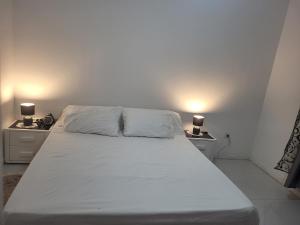 a white bed with two nightstands and two lamps at family apartment in Tizi Ouzou