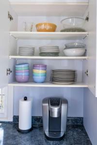 a kitchen shelf with plates and a coffee maker at Coastal Haven in Dennis +21 photos