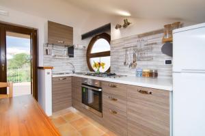 uma cozinha com armários de madeira e um frigorífico branco em Dominella 2 em Casal Velino