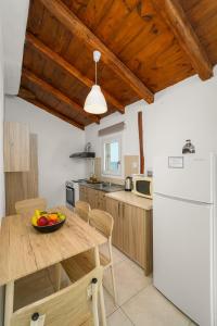 a kitchen with a table and a white refrigerator at Pelagos Home, Liatiko Suite in Kalamaki Heraklion +5 photos