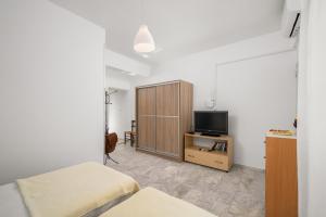 a bedroom with two beds and a tv and a cabinet at Pelagos Home, Liatiko Suite in Kalamaki Heraklion