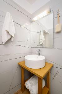 a white bathroom with a sink and a mirror at Pelagos Home, Liatiko Suite in Kalamaki Heraklion