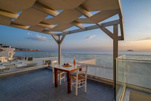 a table and chairs on a balcony with the ocean at Pelagos Home, Liatiko Suite in Kalamaki Heraklion