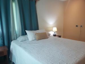 una camera da letto con un letto bianco con tende blu e una lampada di West End Room Shuttle Free a West End