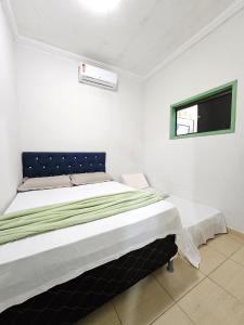 Una cama en una habitación blanca con ventana. en Casa com piscina no centro de Maragogi pertinho da praia!, en Maragogi