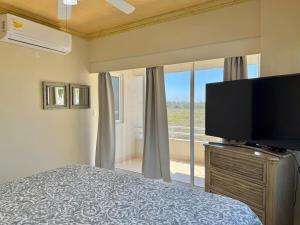a bedroom with a bed and a flat screen tv at Beautiful beachfront space and pool in Mazatlán