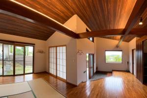 an open living room with wooden ceilings and wood floors at JYUGON KARISOME Nago Okinawa ジュゴンかりそめ 名護沖縄 in Motobu
