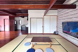 a living room with a table and a tv at JYUGON KARISOME Nago Okinawa ジュゴンかりそめ 名護沖縄 in Motobu