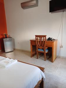 a bedroom with a desk and a bed and a chair at Hotel El Descanso Montelíbano in Montelíbano