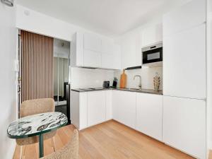 a kitchen with white cabinets and a table and chairs at Cozy Studio with Balcony 2 Guests Paris 16th in Paris +5 photos
