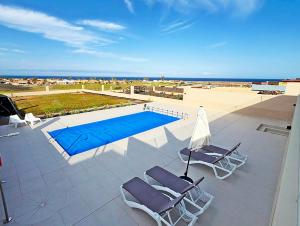 eine Terrasse mit zwei Stühlen und einem Swimmingpool in der Unterkunft Serena Luxury House in Caleta de Fuste