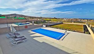 einen Pool auf einem Gebäude mit zwei Stühlen in der Unterkunft Serena Luxury House in Caleta de Fuste