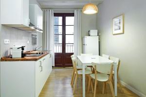 une cuisine avec une table, des chaises et un réfrigérateur dans l'établissement Barcelona Mercaders Apartments, à Barcelone