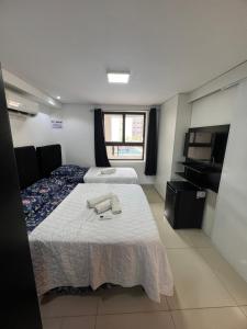 a hotel room with two beds and a television at Flat a 50m da beira-mar do Cabo Branco - Gold Flat 121 in João Pessoa