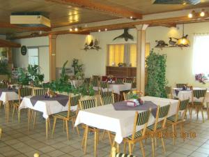 a restaurant with white tables and chairs and plants at Hotel Landhaus Nassau in Meißen