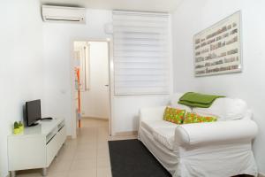 Apartament Conde Güell في برشلونة: غرفة معيشة بيضاء مع أريكة بيضاء وتلفزيون