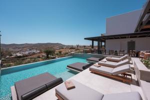 a swimming pool with lounge chairs and a house at Noir Mykonos in Mikonos