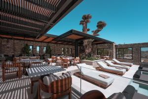 a patio with chairs and tables and a tree at Noir Mykonos in Mikonos