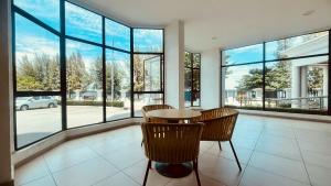a room with a table and chairs and windows at Mutiara Melaka Beach Resort in Kampong Pantai Dusun
