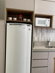 a kitchen with a white refrigerator and a microwave at Apart 202 - Centro Histórico in Itu