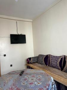 a bedroom with a couch and a tv on the wall at Bel appartement à Adrar Agadir in Agadir