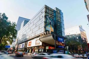 una strada trafficata con auto che passano davanti a un edificio di 深圳华尔曼欢朋酒店公寓 罗湖水贝珠 宝城店 a Shenzhen