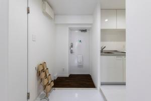 eine Küche mit weißen Wänden und einem Flur mit einem Stuhl in der Unterkunft AMP FLAT Daimyo 702 in Susakiuramachi