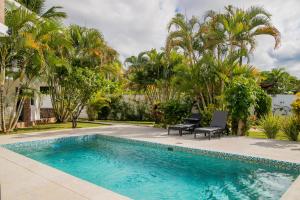 a swimming pool with two chairs and palm trees at Hotel Casa Pierretta in Las Terrenas