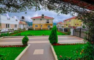 a view of a house with a green yard at Maria villa in Ooty