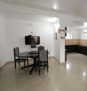a dining room with a table and chairs and a tv at Maria villa in Ooty