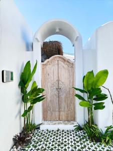 a wooden door in a white house with plants at Villa Vinodayan Uluwatu by LODGELINK BALI in Uluwatu