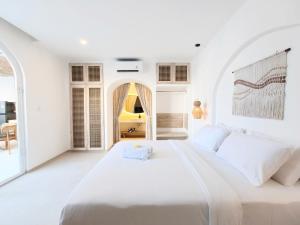 a white bedroom with a large bed and a mirror at Villa Vinodayan Uluwatu by LODGELINK BALI in Uluwatu
