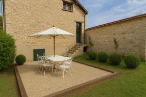 einen Tisch und Stühle mit Sonnenschirm im Hof in der Unterkunft La Folie Giverny - Villa Premium - 3 Suites VIP - 8 Pièces 150M2- Centre Village - Maison privatisée -Jardin paysagé - Parking- in Giverny