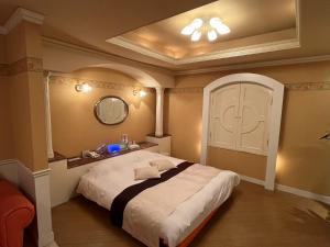 a bedroom with a large white bed with a mirror at ホテル湯島御苑水戸店 in Mito