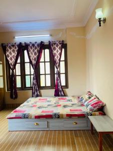 a bed in a room with two windows at Madame Flexstay Girls Hostel in Kathmandu