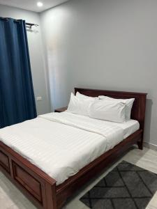 a bed with white sheets and a blue curtain at Akwaaba Apartments in Chipata