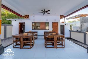 une salle à manger avec des tables et des chaises en bois dans l'établissement Seashell Bingin Villas by Bukit Vista, à Uluwatu