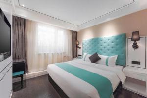 a bedroom with a large bed with a blue headboard at Xana Lite Beijing Sidaokou Dazhong Temple Metro Station Branch in Beijing