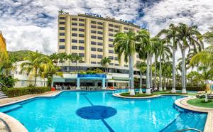 un hotel con una gran piscina y palmeras en Hotel Olé Caribe, en Macuto