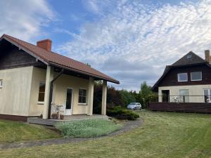 a house with a porch and a car parked in the yard at Jūrlejas in Kaltene