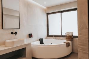 a bathroom with a tub and a sink and a window at Sagredo Boutique Hotel & Spa in Ágios Fokás